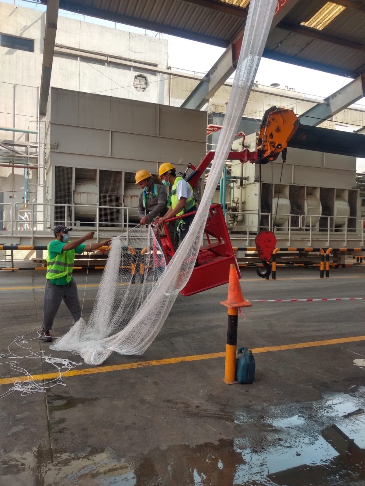 Installation crew rigging industrial safety net with crane lift in Karachi