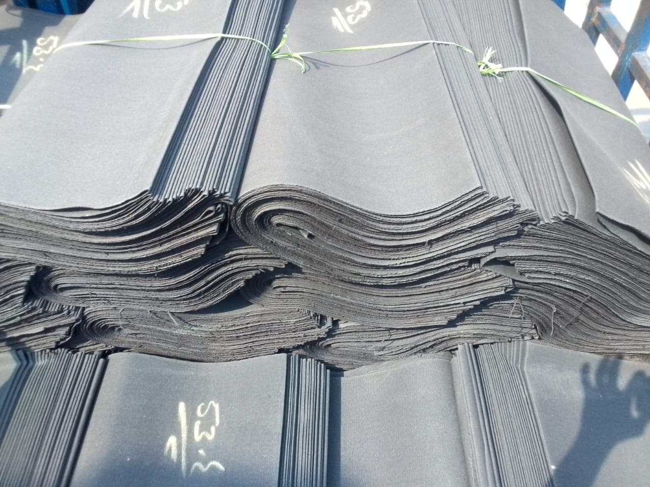 Heavy black rubberized waterproof canvas tarpaulin sheets loaded for truck transport in Karachi