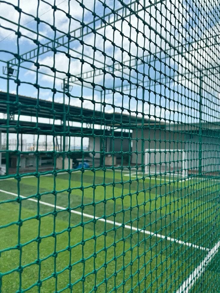 Knotted green sports netting installed on futsal turf court Karachi